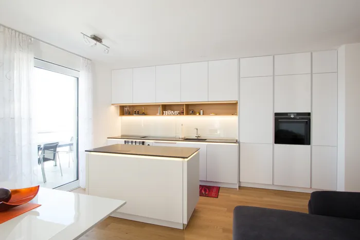 Moderne weiße Einbauküche mit Kochinsel und Holzfußboden