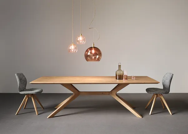 Moderner Esstisch aus Holz mit zwei grauen Stühlen und Hängelampen in Kupferoptik