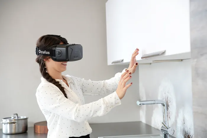 Frau mit Oculus VR-Headset interagiert in virtueller Realität in moderner Küche