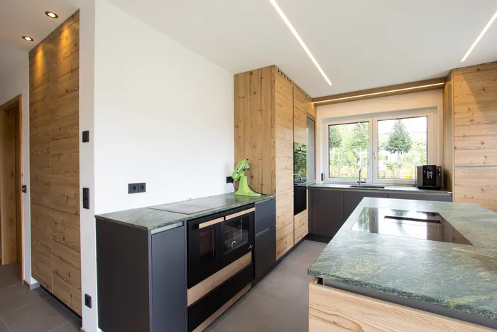 Moderne Einbauküche mit Naturstein-Arbeitsplatten und Holzfronten