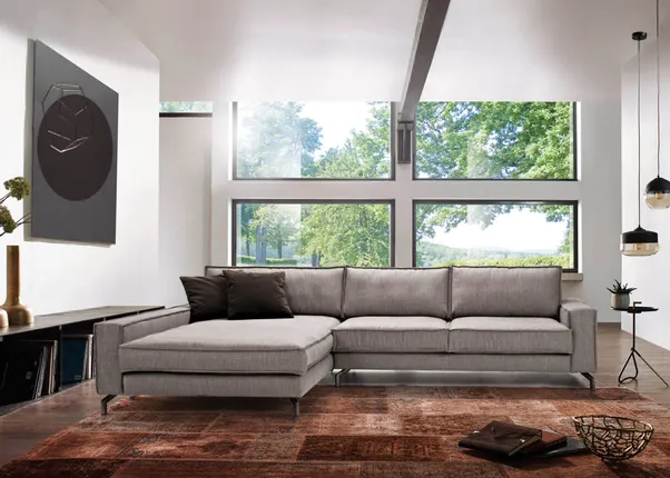 Modernes Wohnzimmer mit grauem Ecksofa, großen Fenstern und braunem Teppich