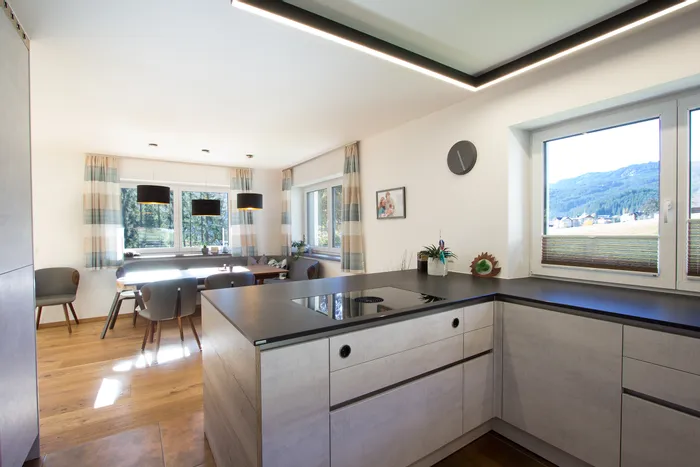 Moderne Küche mit Kochinsel, Essbereich und Blick auf Berge durch große Fenster