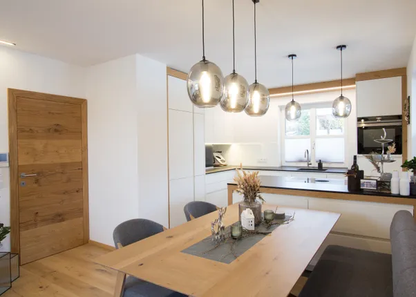 Moderne Küche mit Holzdetails, Hängelampen und Essbereich mit Dekoration