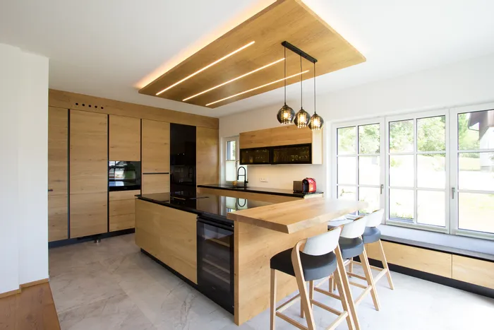 Moderne Küche mit Holzfronten, Kücheninsel, Hängelampen und großen Fenstern