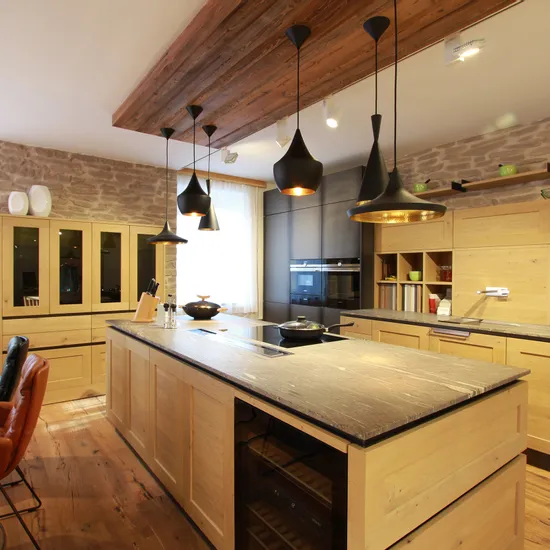 Moderne Küche mit Holzmöbeln, Kücheninsel, Hängelampen und Steinwand