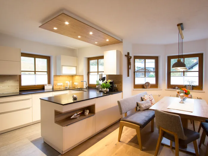 Moderne Wohnküche mit Essbereich, Holzakzenten und großen Fenstern