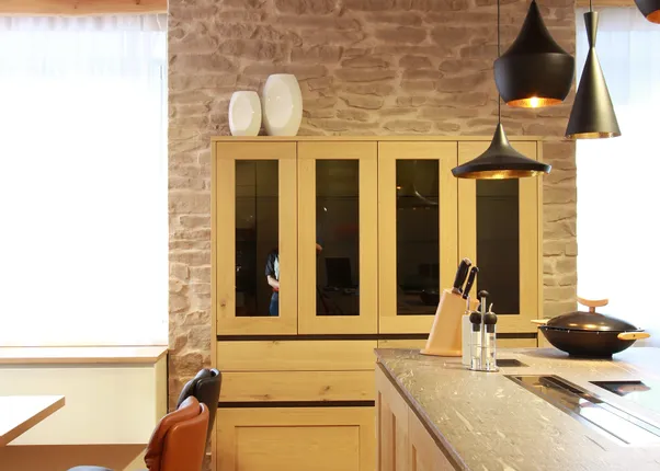 Moderne Einbauküche mit Holzfronten, Kochinsel, Hängelampen und Ledersesseln am Esstisch