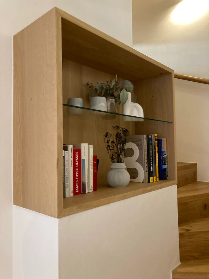 Moderne Holz-Wandregal mit Büchern, Vasen und Deko neben Treppe