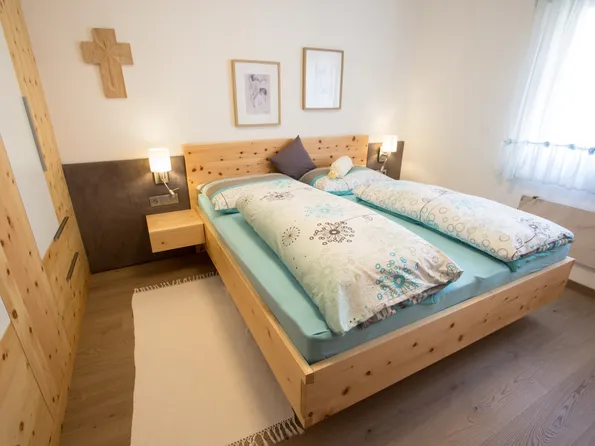 Modernes Schlafzimmer mit Doppelbett aus hellem Holz und gemusterten Bettdecken