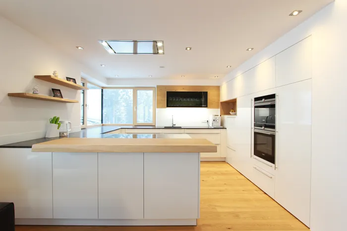 Moderne weiße Einbauküche mit Holzarbeitsplatte und integriertem Backofen