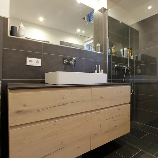 Modernes Badezimmer mit Holzwaschtisch, Glasdusche und Waschmaschine