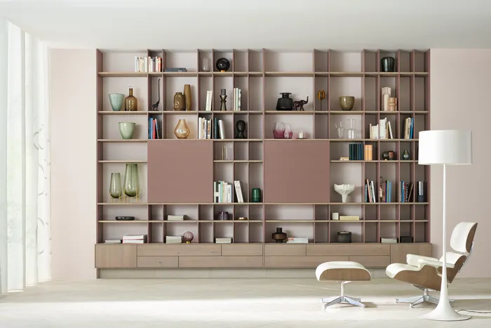 Modernes Wohnzimmer mit braunem Bücherregal, Dekoobjekten und Eames Lounge Chair