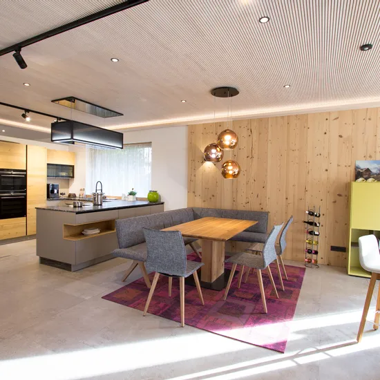 Moderne offene Wohnküche mit Holzelementen, Kücheninsel, Esstisch und stilvollen Lampen