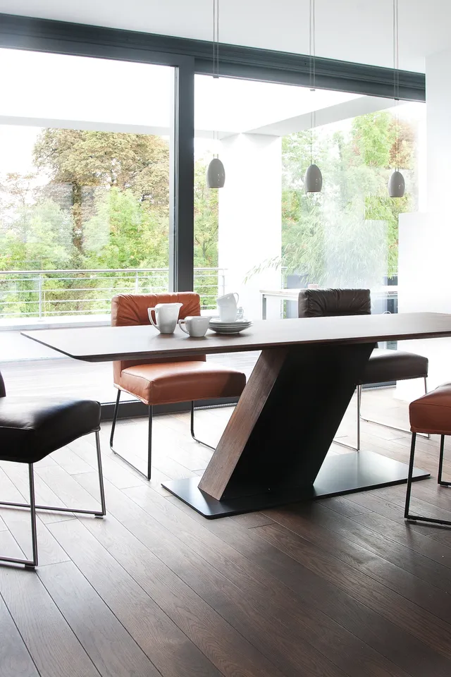 Modernes Esszimmer mit Holzfußboden, Designerstuhl und großem Esstisch vor Panoramafenstern