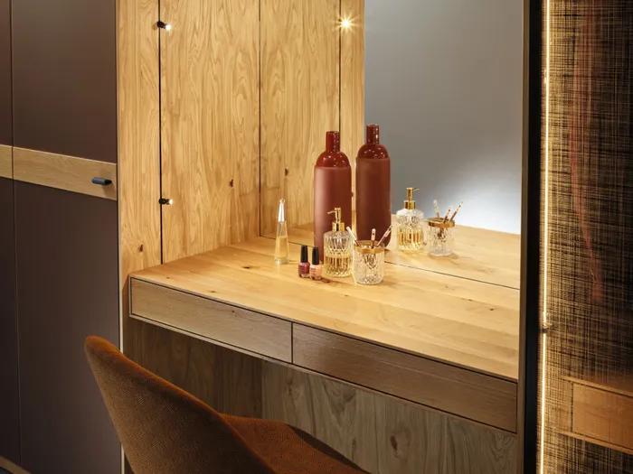 Moderner Schminktisch aus Holz mit Spiegel, Parfümflakons und braunem Stuhl in elegantem Innenraum