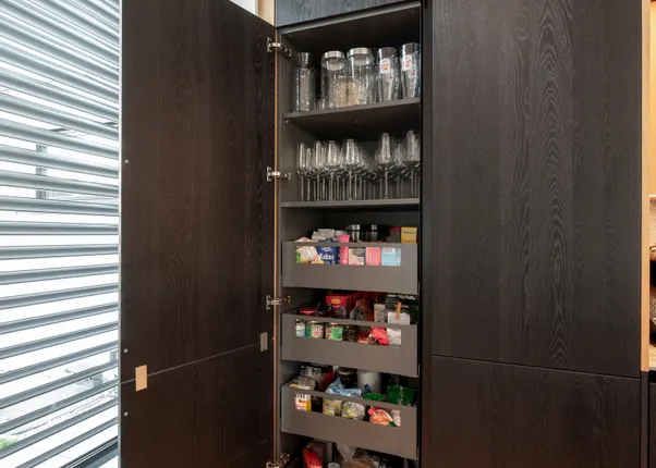 Geöffneter Küchenschrank mit Gläsern, Vorratsdosen und Lebensmittelregalen in modernem Design
