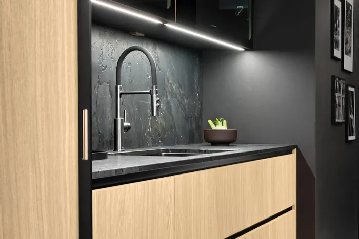 Moderne Küchenspüle mit schwarzer Steinplatte, Holzfronten und LED-Beleuchtung