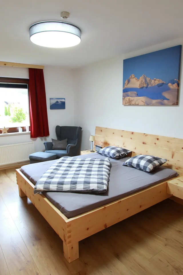 Modernes Schlafzimmer mit Holzmöbeln, Doppelbett und rot dekoriertem Fenster