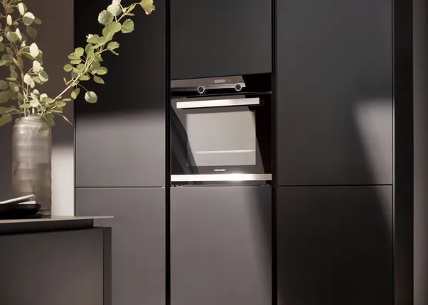 Moderne schwarze Küchenzeile mit eingebautem Backofen und stilvoller Dekoration