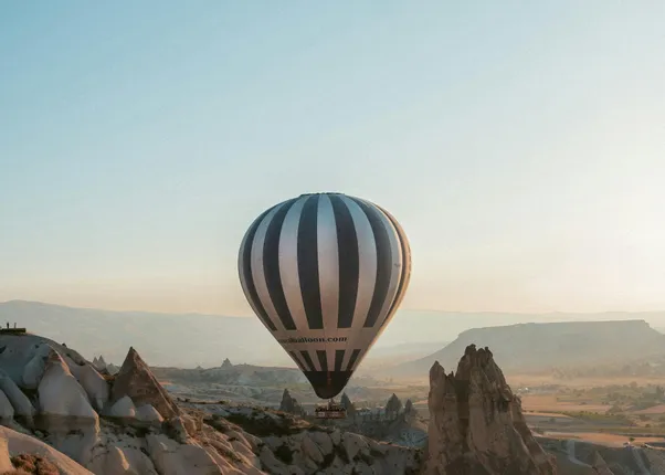 Heißluftballon fliegt über Felsformationen in Kappadokien bei Sonnenaufgang