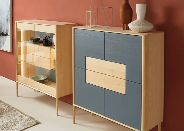 Moderne Holzkommoden mit Glasvitrine und grauen Fronten vor roter Wand