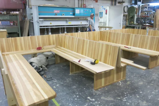 Holzbänke in L-Form im Bau in einer Tischlerei mit sichtbaren Maschinen und Werkzeugen