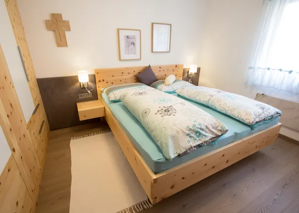 Modernes Schlafzimmer mit Doppelbett aus hellem Holz und gemusterten Bettdecken