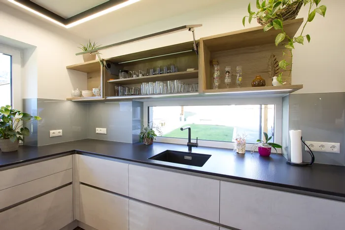 Moderne Küche mit offenem Hängeschrank, Spüle, Hauspflanzen und großem Fenster mit Gartenblick