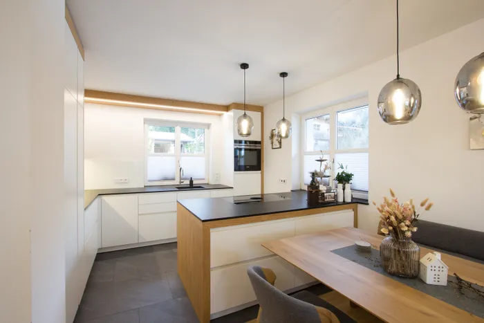 Moderne weiße Einbauküche mit Kochinsel, Holzdetails und stilvoller Essbereich mit Dekoration