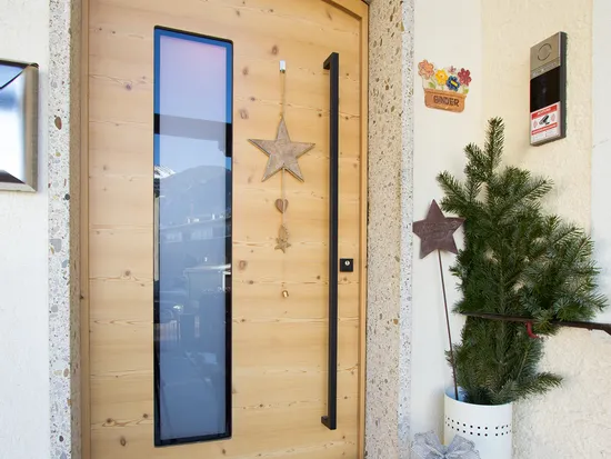 Holzeingangstür mit Weihnachtsdeko, Geschenk, Fussmatte und kleiner Tanne daneben