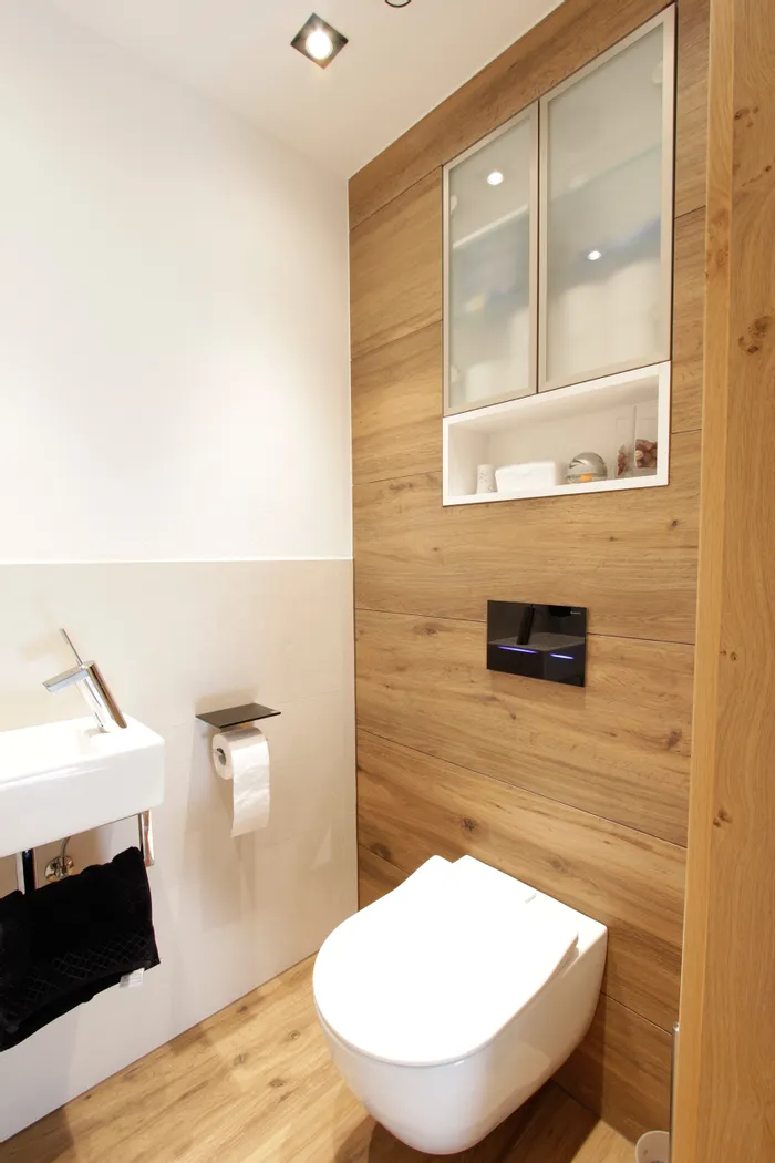 Modernes WC mit Holzverkleidung, Hängetoilette, Waschbecken und integriertem Spiegelschrank