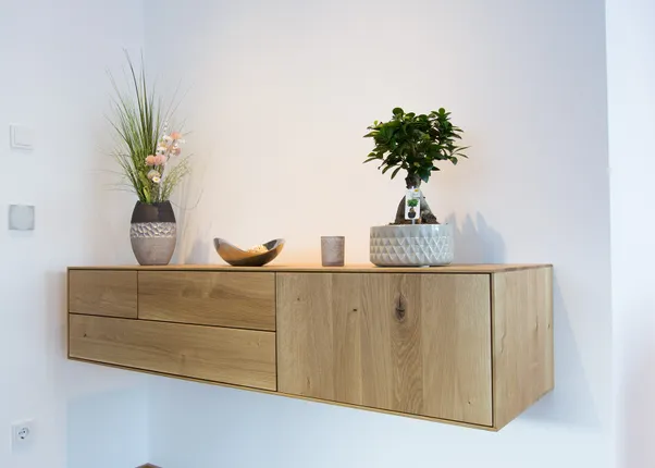 Moderne Wandkonsole aus Holz mit Zierpflanzen und Deko in einem hellen Raum