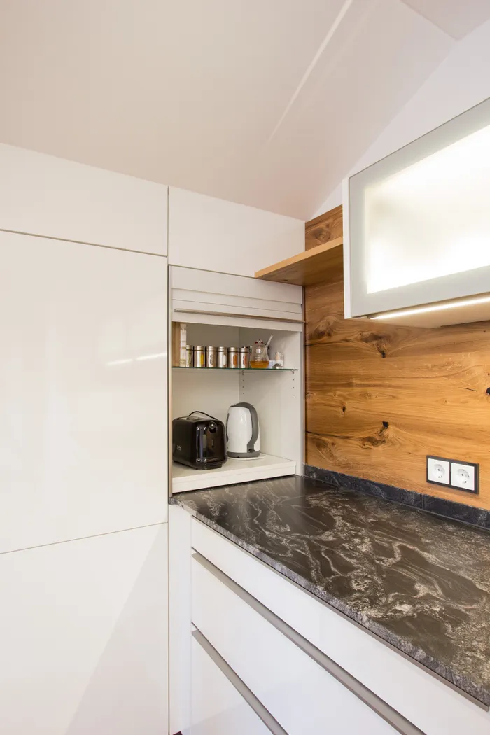 Moderne Küchenecke mit Toaster, Wasserkocher und Gewürzregal in einem weißen Einbauschrank