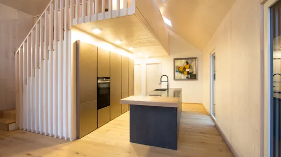 Moderne offene Küche mit Holzverkleidung, Kochinsel und Einbauschränken in Goldoptik