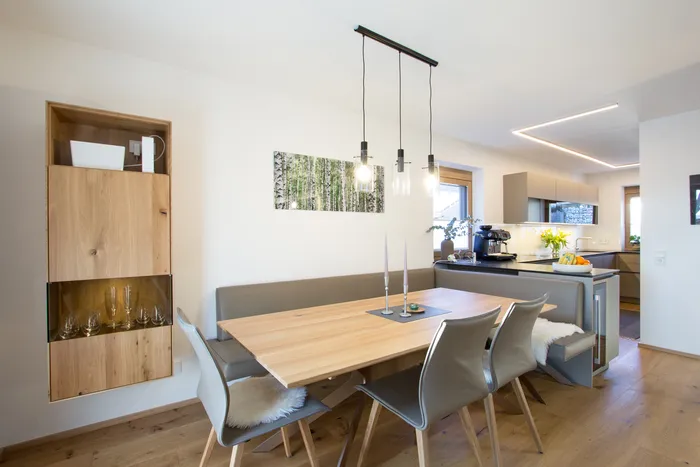 Moderne Wohnküche mit Essbereich, Holzstuhlmöbeln und Hängelampen im skandinavischen Stil