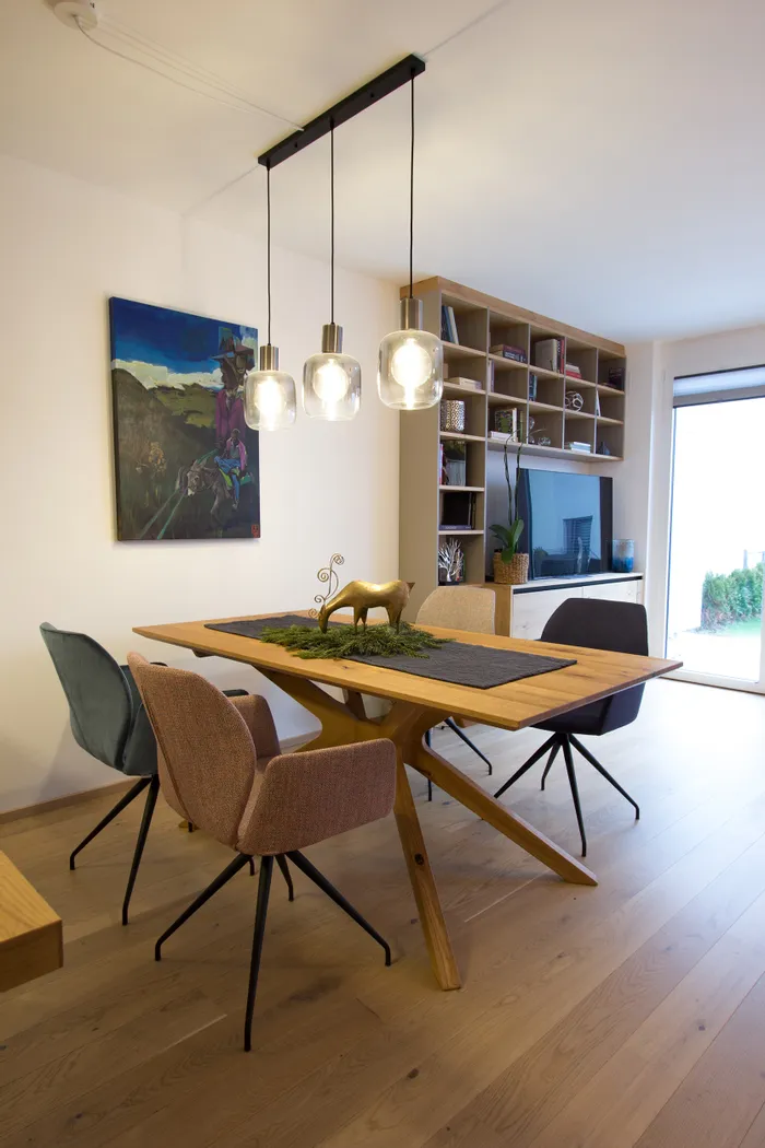 Modernes Esszimmer mit Holztisch, Polsterstühlen und Designer-Hängelampen