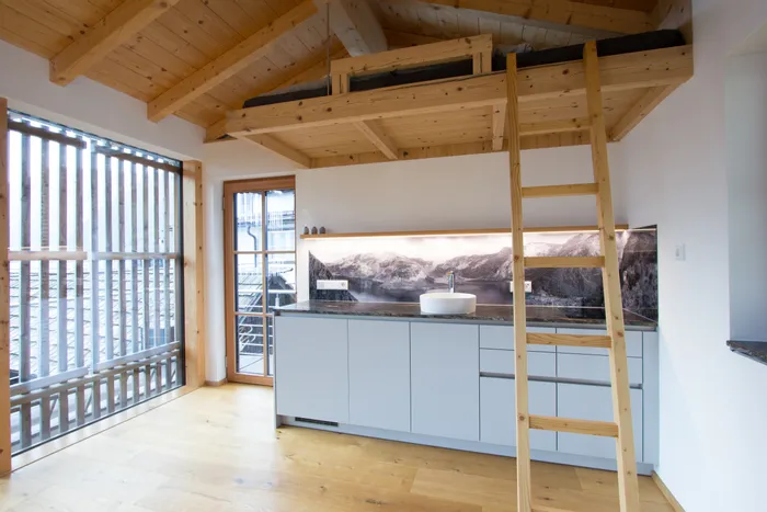 Moderne kleine Küche mit Holzleiter zu einem Hochbett und Alpenpanorama als Rückwand