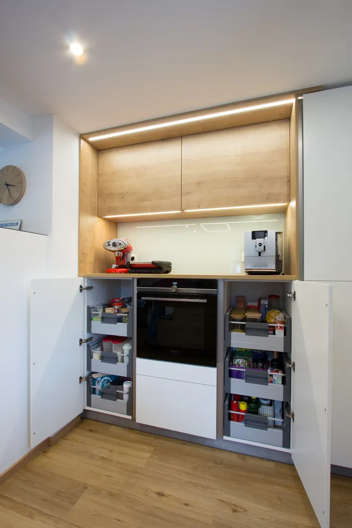 Moderne Einbauküche mit geöffneten Vorratsschränken und integriertem Backofen
