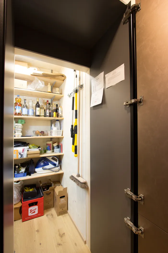 Aufgeräumte Abstellkammer mit Regalen voller Vorräte, Getränken, Reinigungsmitteln und Haushaltsgeräten