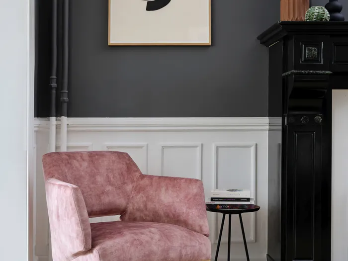 Rosa Polstersessel mit Holzbeinen in modernem Wohnzimmer mit schwarzem Kamin und Wandkunst