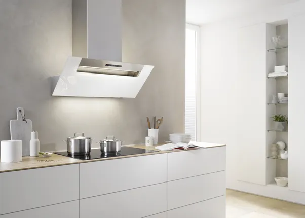 Moderne weiße Küche mit Dunstabzugshaube und induktivem Kochfeld mit zwei Edelstahltöpfen