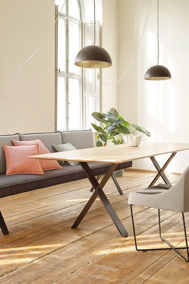 Moderner Essbereich mit Holztisch, gepolsterten Stühlen und Sofa vor großen Fenstern