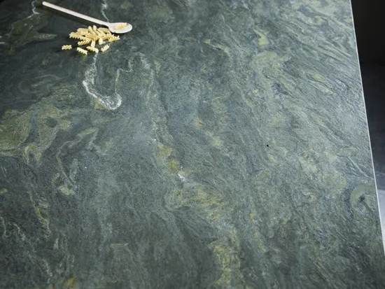 Grüne Küchenarbeitsplatte aus Naturstein mit Induktionskochfeld und Kochutensilien