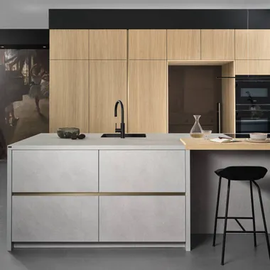 Moderne Küche mit hellem Betoninselblock, Holzfronten und schwarzem Wasserhahn