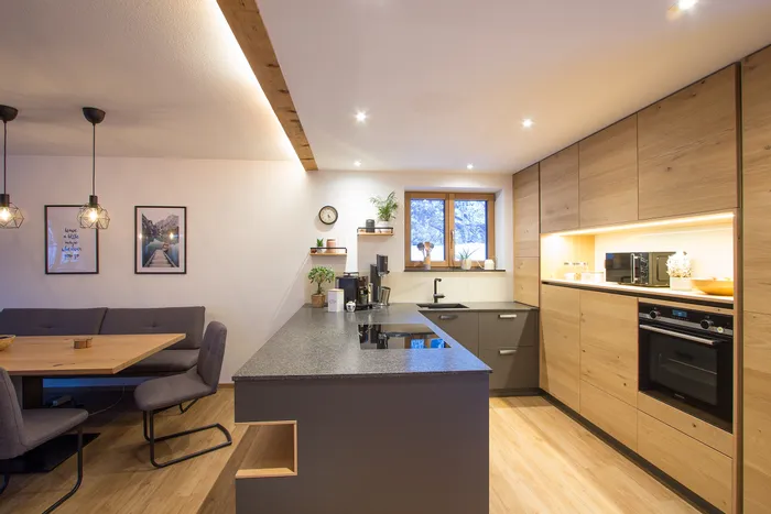 Moderne Einbauküche mit Holzfronten, Kücheninsel und gemütlicher Essecke