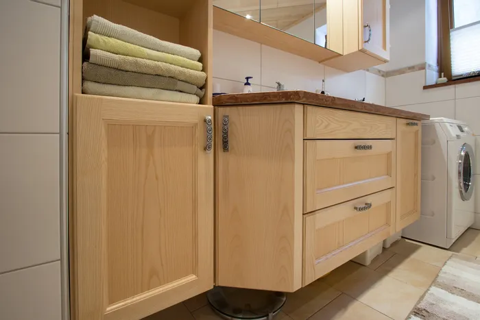 Modernes Badezimmer mit Holzunterschränken, gefalteten Handtüchern und einer Waschmaschine