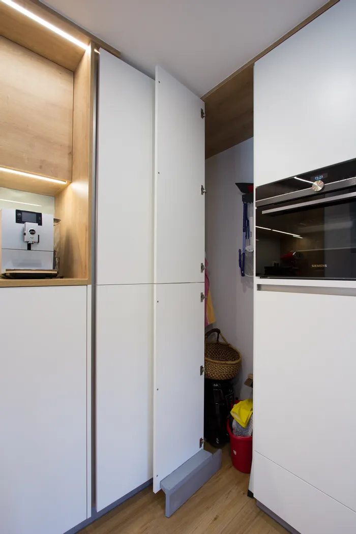 Geöffneter Küchenschrank mit Besenschrank und Haushaltsutensilien im modernen Design