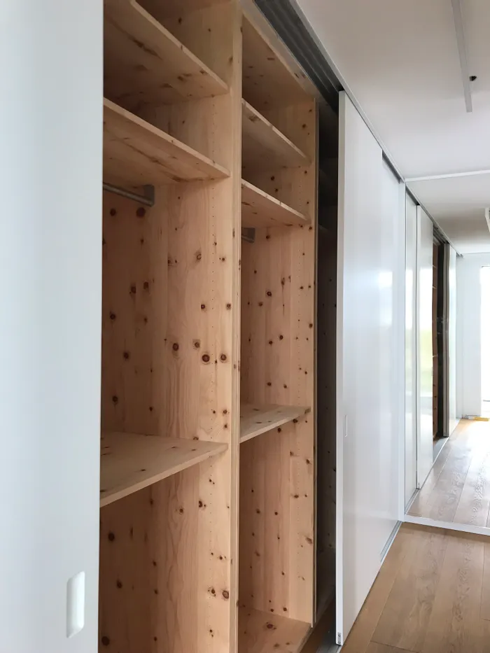 Offener, maßgefertigter Einbauschrank aus hellem Holz mit Schiebetüren in modernem Flur