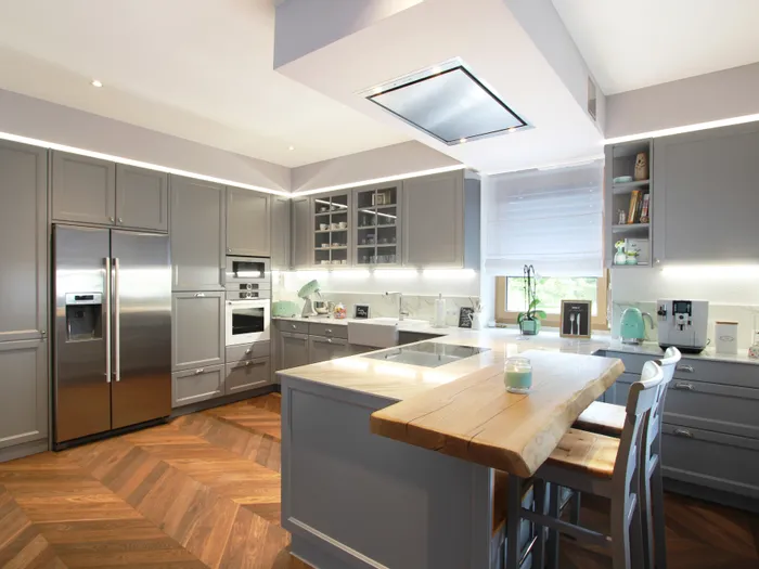 Moderne graue Einbauküche mit Kücheninsel, Holzboden und hochwertigen Elektrogeräten