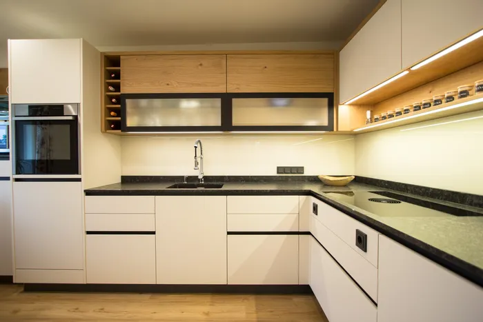 Moderne Einbauküche mit matten Fronten, schwarzer Arbeitsplatte und Holzdetails